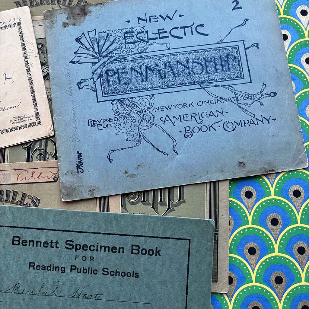 a stack of 1800s penmanship copy books