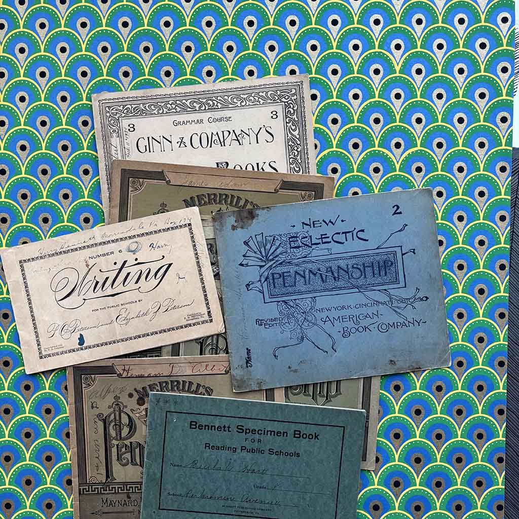 a stack of 1800s penmanship copy books