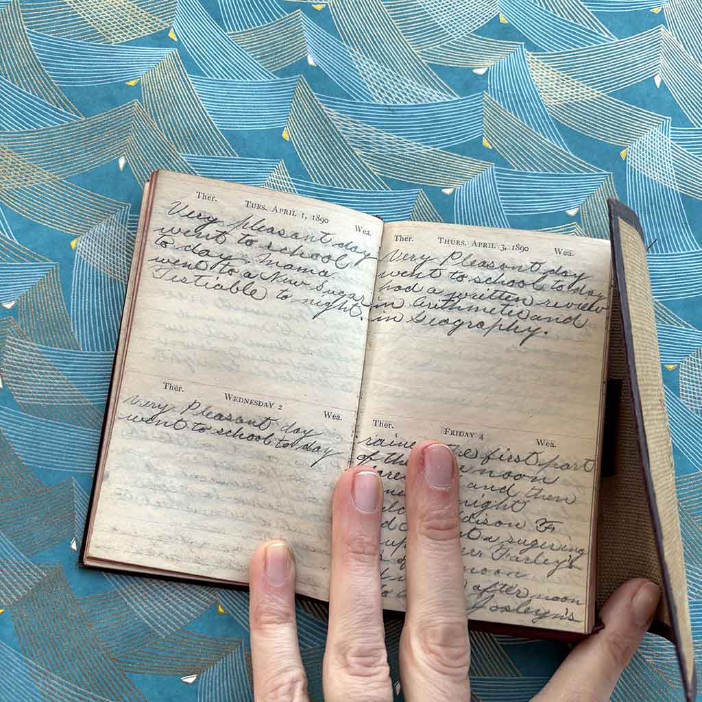 a hand holds open a 1890 Standard Diary